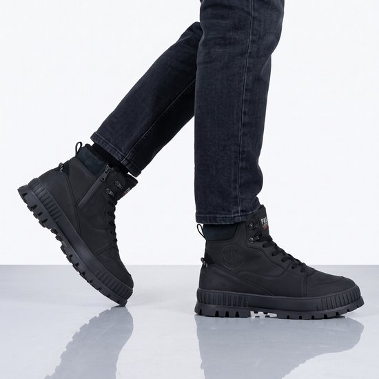 Bottines noires Palladium Pallashock aux pieds d'un mannequin portant un jean foncé.