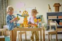 Deux enfants construisent avec des jeux LEGO DUPLO sur une table en bois dans une chambre d'enfant colorée.
