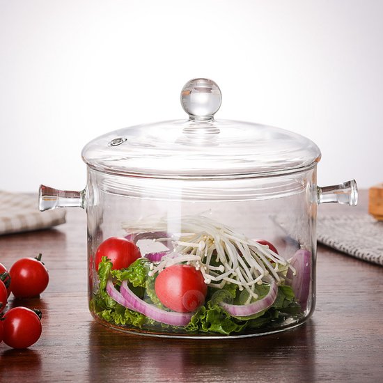Glazen kookpan met deksel en handgrepen, gevuld met sla, rode ui, tomaat en enoki-paddenstoelen op een houten tafel.