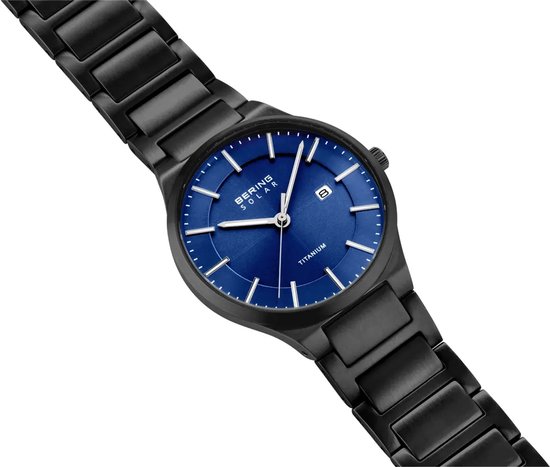 Zwart titanium horloge met blauwe wijzerplaat, datumvenster en zilverkleurige indices en wijzers.