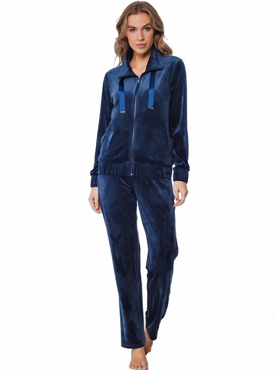 Model draagt een donkerblauw fluwelen huispak met ritssluiting, opstaande kraag en elastische boorden.