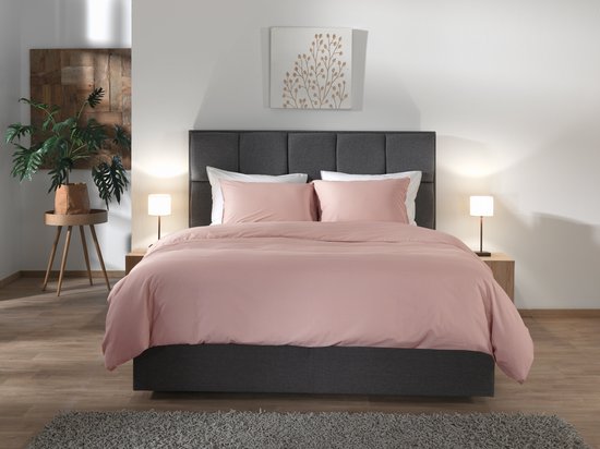 Bed opgemaakt met een dekbedovertrek in roze 'Haze Coral' gewassen katoen, geflankeerd door twee tafellampen.