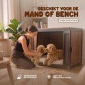 Vrouw geeft bruine hondenkuffel aan een hond in een hondenmand.