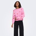 Model lachend in een roze gebreide trui met rode hartjesprint en zwarte wijde broek.