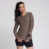 Model draagt een bruin sportshirt met lange mouwen, zwarte shorts en een sporthorloge.
