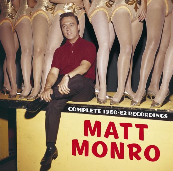 Matt Monro zit op een podium, met een rood shirt en zwarte broek, omringd door benen van danseressen in glimmende outfits. Tekst: COMPLETE 1960-62 RECORDINGS MATT MONRO.