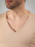 Borst van een man met een beige v-hals t-shirt.