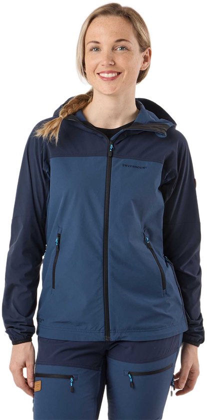 Model in een donkerblauwe jas en broek. De jas heeft twee tinten blauw en een capuchon. 'SWEDEMOUNT' op de borst.