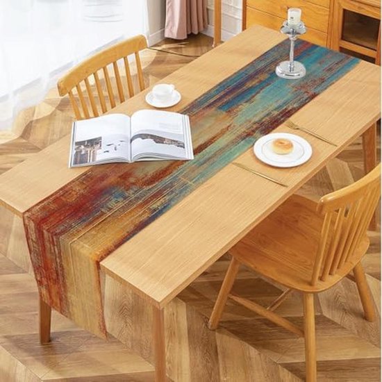 Longue table en bois avec un chemin de table à imprimé abstrait dans des tons brun rouille, orange, beige et bleu.