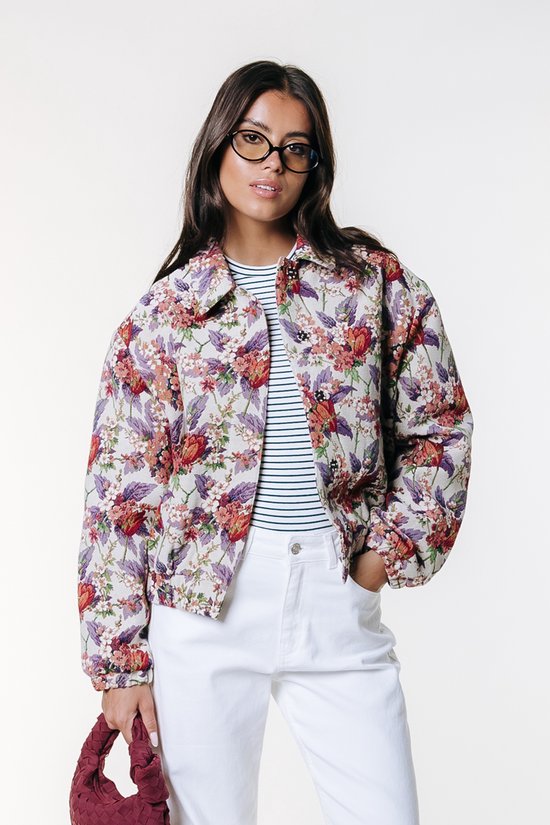 Model in geborduurd bomberjack met bloemenprint in paars, rood en groen. Combineert met gestreepte top en witte wijde broek.
