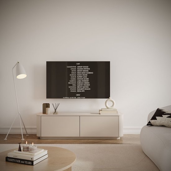 Een beige tv-meubel met twee deuren staat in een woonkamer, met een tv erop die castinformatie toont.