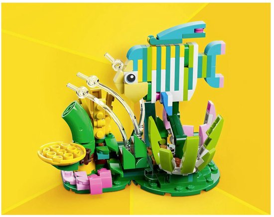 Poisson LEGO coloré aux rayures jaunes, vertes et bleues, entouré de plantes vertes et roses.