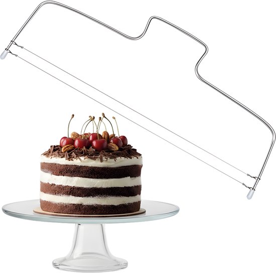 Een gedecoreerde chocoladetaart met kersen en noten op een glazen taartschaal.