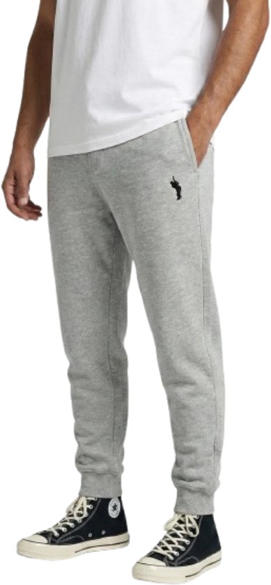Lichtgrijze joggingbroek met zwart logo op de linkerheup, gedragen door een model.