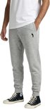 Lichtgrijze joggingbroek met zwart logo op de linkerheup, gedragen door een model.