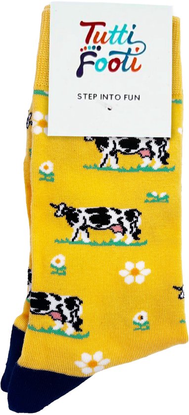 Gele sokken met een patroon van koeien en bloemen, met het merk 'Tutti Footi'. Donkerblauwe tenen en hielen.