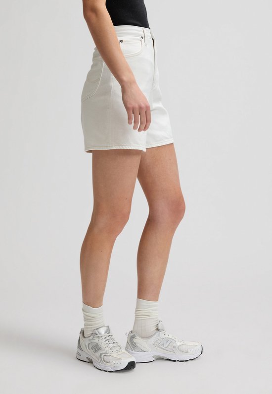 Zijzicht van een vrouw in een witte spijkerbroekshort met wijde pijpen.