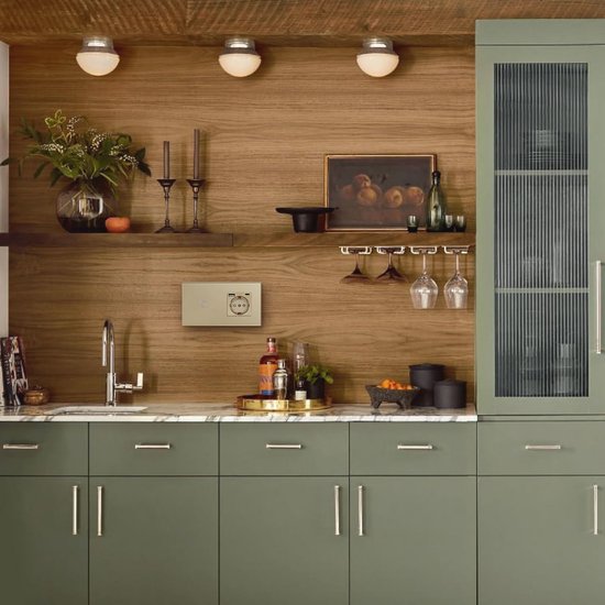 Gouden wandcontactdoos met schakelaar en USB-poorten geïnstalleerd in een moderne keuken met groene kasten.