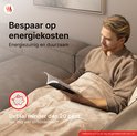 Man leest op bank onder beige deken. Tekst: 'Bespaar op energiekosten. Energzuinig en duurzaam. Betaal minder dan 20 cent per dag aan stroomkosten*'.