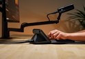 Een hand bedient de zwarte XLR Dock met microfoon en monitor op een bureau.