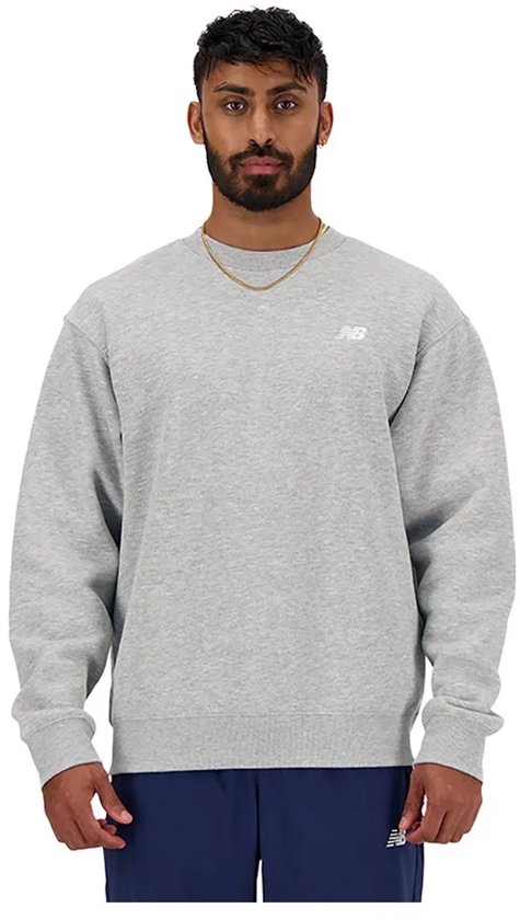 Man met baard draagt een grijze New Balance sweater met een klein wit logo.