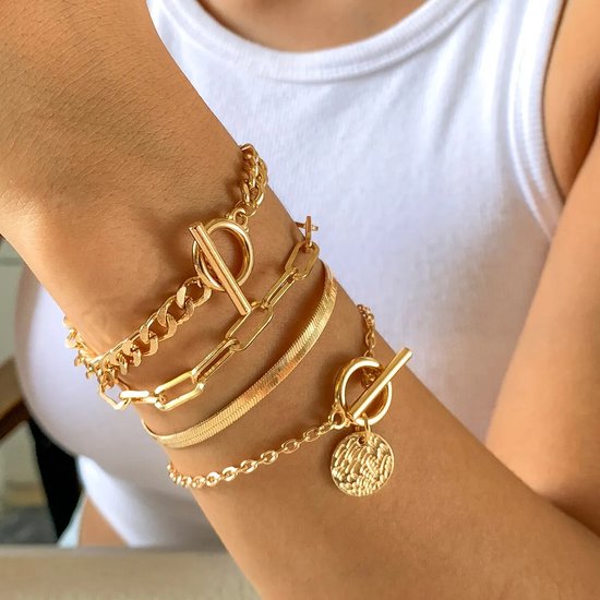 Drie gouden armbanden met schakels en muntsluiting, gedragen op een pols.