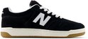 Zwarte suède New Balance sneakers met witte N-logo's, witte veters en bruine zool.