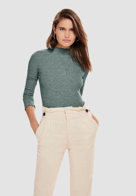 Groene coltrui met lange mouwen, gedragen door een vrouw met een beige broek met hoge taille en knopen.