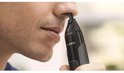 Man trimt neus met zwarte Philips neustrimmer.