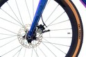 Close-up van de schijfrem en voorwiel van een paarse Rinos gravelbike met "CST TRENT" band.