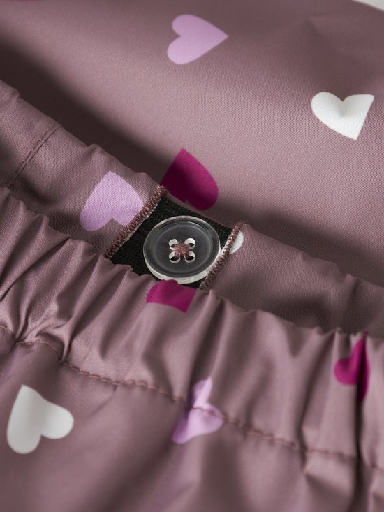 Detail van roze regenbroek met all-over hartjesprint en een knoopsluiting.