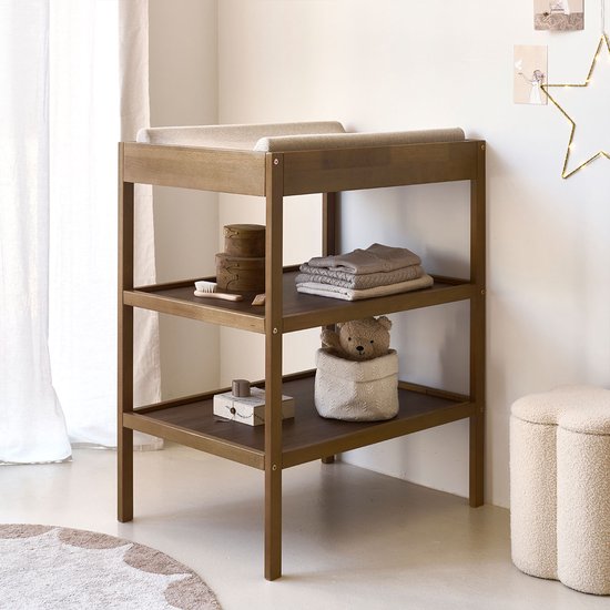 Bruine houten commode met aankleedkussen en opbergvakken, met een teddybeer.