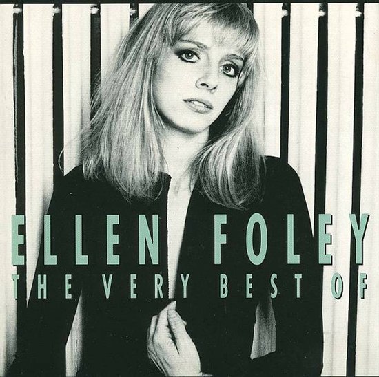 Ellen Foley, langharige blondine met donkere jas, staand voor verticale witte en zwarte strepen.