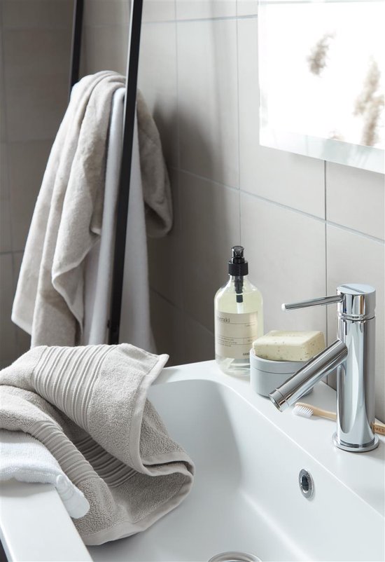 Salle de bain avec un lavabo blanc, un robinet, un distributeur de savon, du savon et des serviettes.