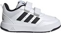 Witte peutersneaker van Adidas met zwarte strepen en klittenbandsluiting, gefotografeerd in een lege ruimte.