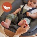 Baby ligt in een grijze babyset met harnas. Iemand raakt de voetjes aan. Veer-icoon.