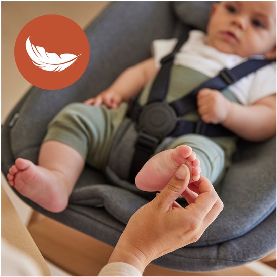 Baby ligt in een grijze babyset met harnas. Iemand raakt de voetjes aan. Veer-icoon.