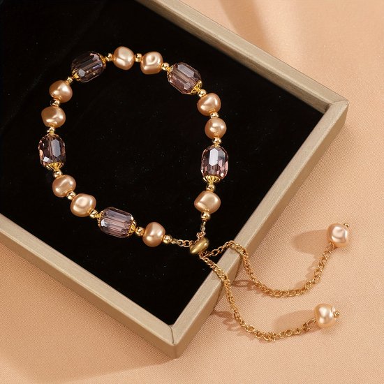 Gouden armband met crème parels en lichtroze facetkralen in een geschenkdoos. Verstelbaar met gouden ketting.