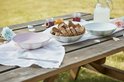 Picknicktafel met kommen, brood en jam. Kom met paarse en witte strepen.