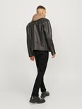 Man in zwarte jeans en bruine hoodie onder zwart leren jack, staand, achterkant.