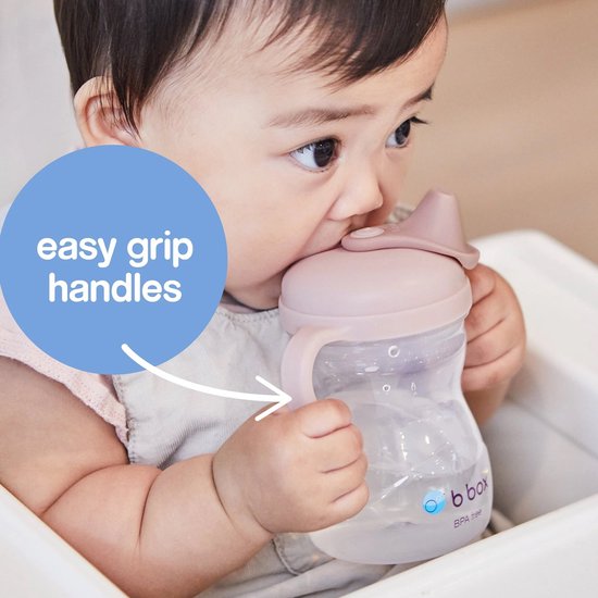 Bébé tenant une tasse b.box rose avec poignées. Texte : easy grip handles.