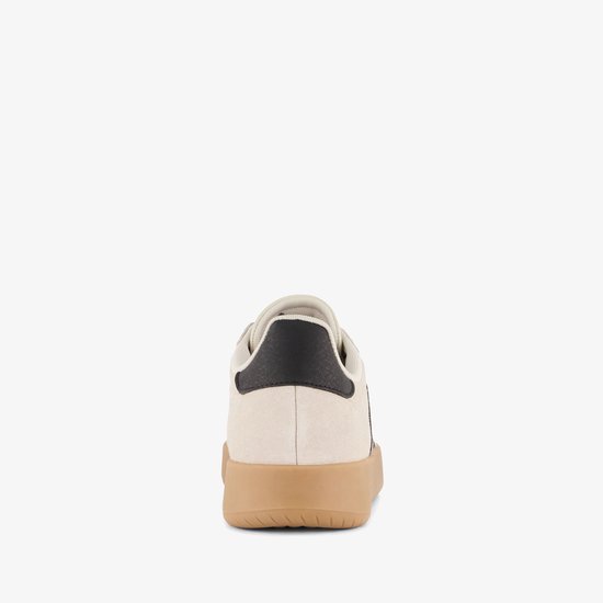 Achterkant van een beige Adidas sneaker met zwarte hielkap en gumkleurige zool.