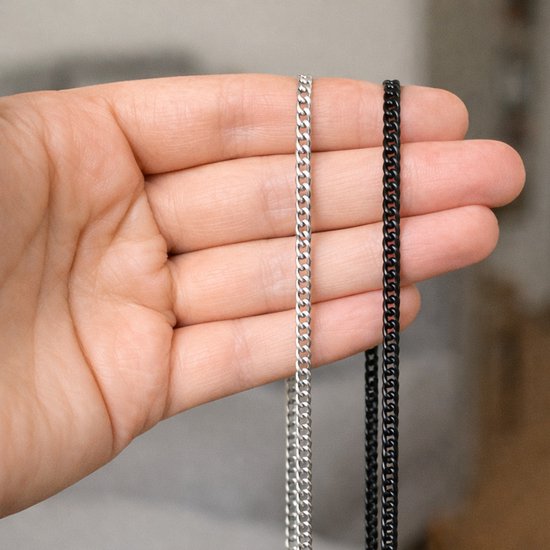 Hand met een zilverkleurige en een zwartkleurige Cubaanse koord ketting.