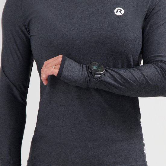 Een vrouw draagt een donkergrijs sportshirt met lange mouwen en duimmanchetten. Op de borst is het 'R' logo zichtbaar. Ze checkt haar sporthorloge.