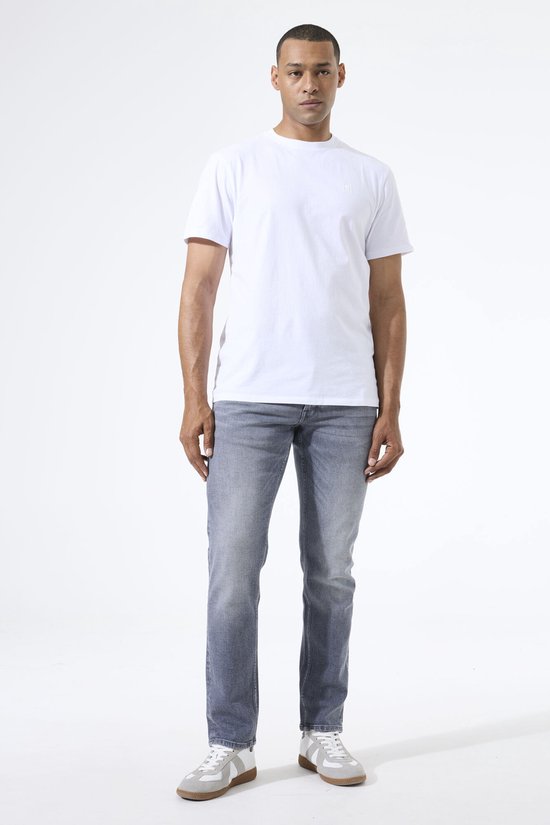 Man met witte t-shirt en grijze Garcia jeans. De jeans hebben een lichte wassing en tapered fit.