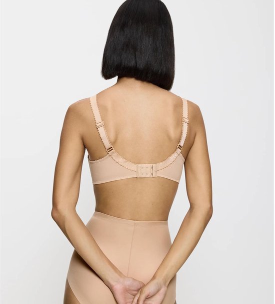 Gezichtspunt van achteren: een vrouw met een korte bob draagt een beige kanten beha en hoge bikinislip. Haar handen zijn achter haar rug gevouwen.