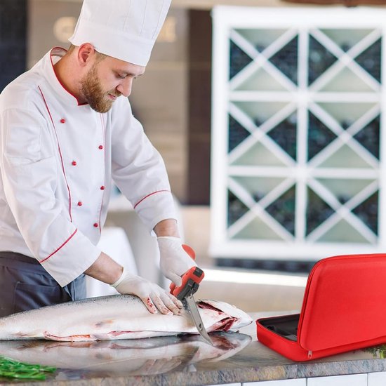 Chef in witte koksbuis snijdt zalm met rood elektrisch mes. Rode koffer ligt op de toonbank.