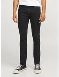 Man met zwarte jeans en wit T-shirt, staand op een lichte achtergrond.