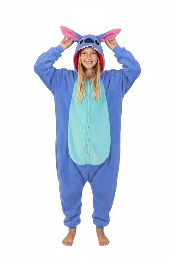 Blauw Stitch onesie met capuchon en oren. Een meisje met blonde haren, zonder schoenen, poseert met de handen op haar hoofd.
