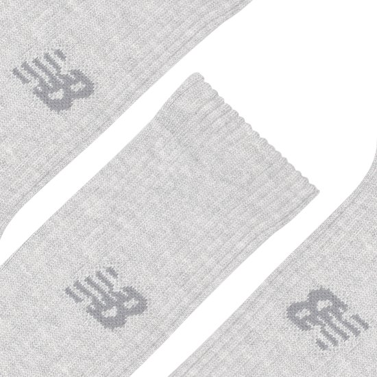 Close-up van drie lichtgrijze New Balance sportsokken met logo.